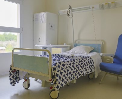 Chambre individuelle avec lit médical, fauteuil et armoire